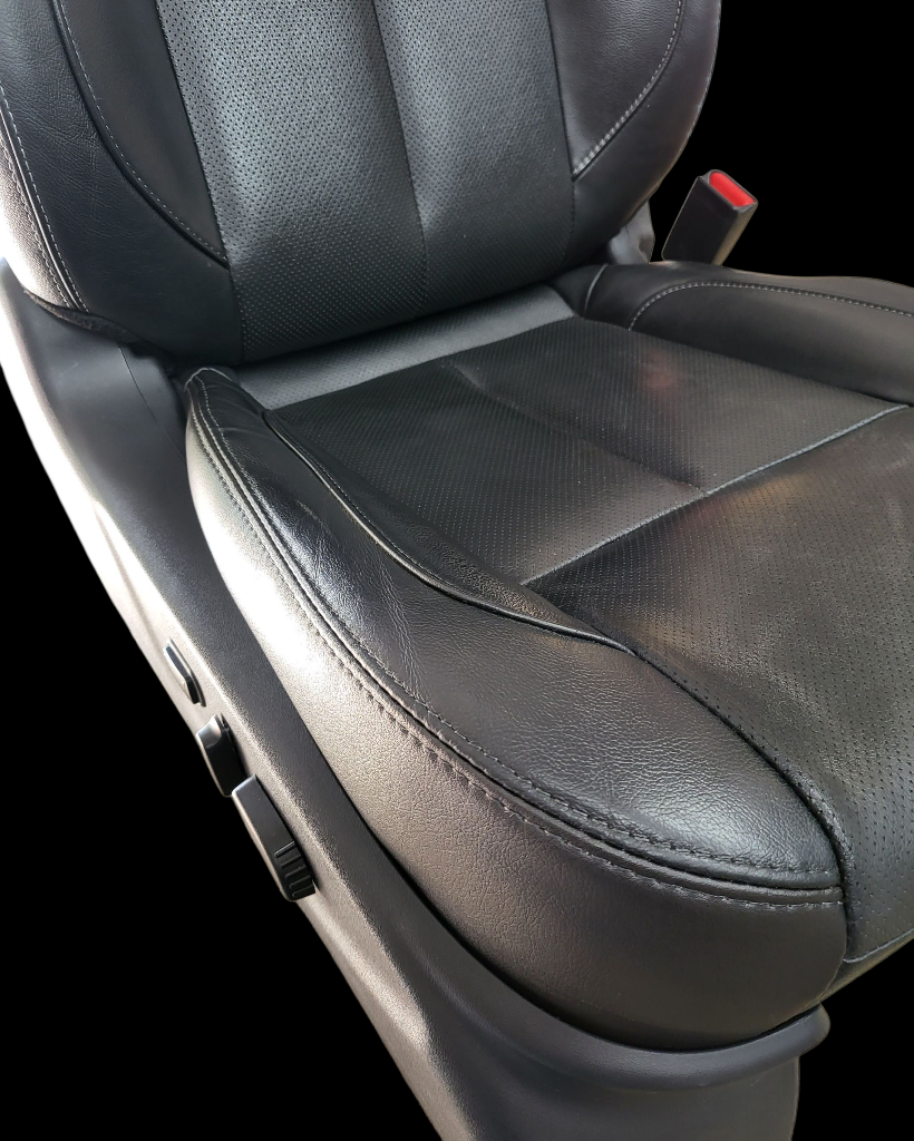 Black leather car seat with perforated upper section and stitching detail, with side controls visible.