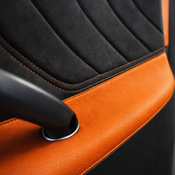 Car dashboard detail: black textured surface with white stitching, round air vent, and gauges.