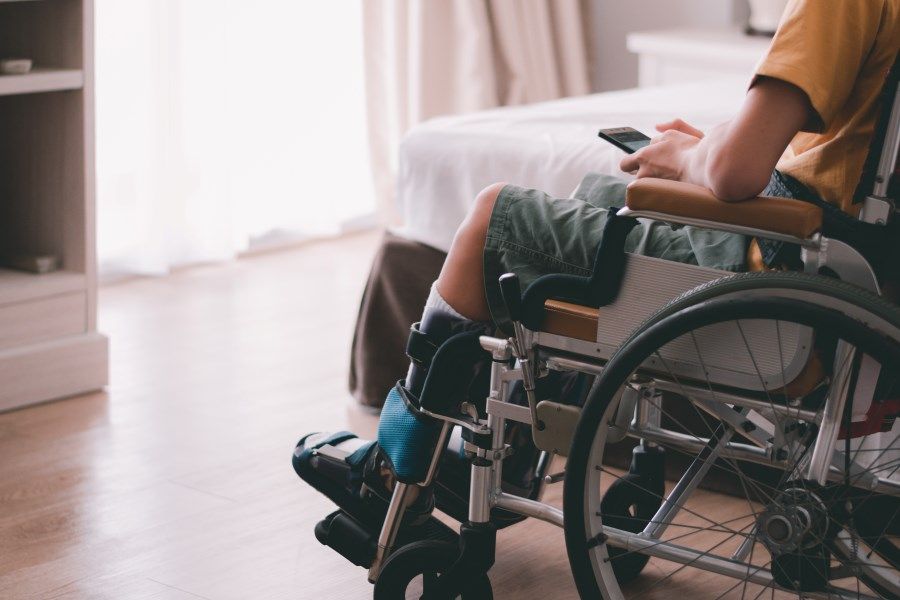 Person in a Wheelchair in a Room, Holding a Phone — Ballina Home Healthcare Sales & Hire and Compression Stockings Plus in Ballina, NSW