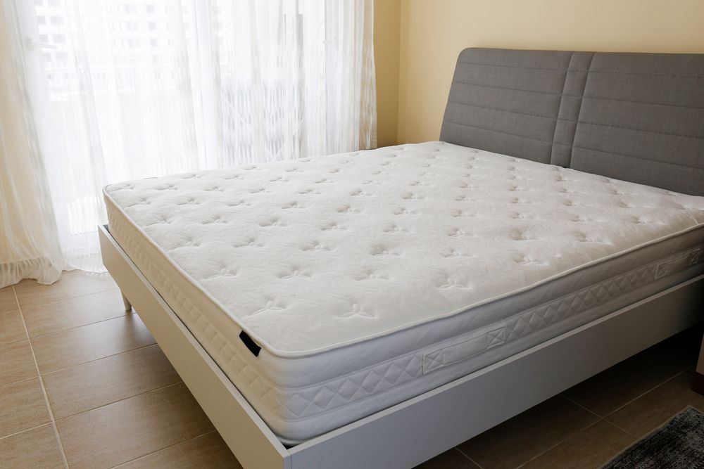 Queen-sized Bed With a Gray Headboard and White Mattress in a Bedroom — Ballina Home Healthcare Sales & Hire and Compression Stockings Plus in Ballina, NSW