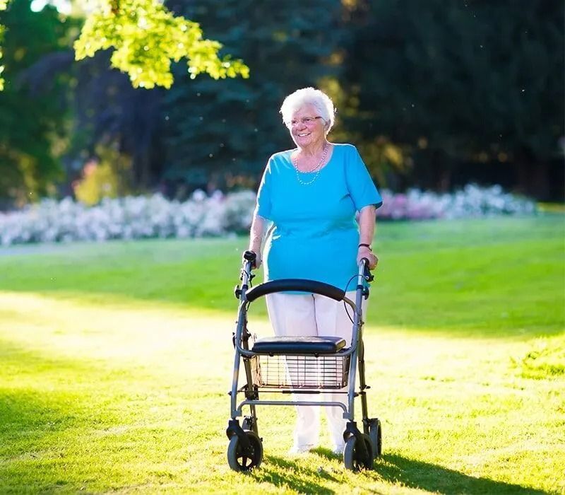 Smiling Elderly Woman in Park, Using a Walker — Ballina Home Healthcare Sales & Hire and Compression Stockings Plus in Ballina, NSW