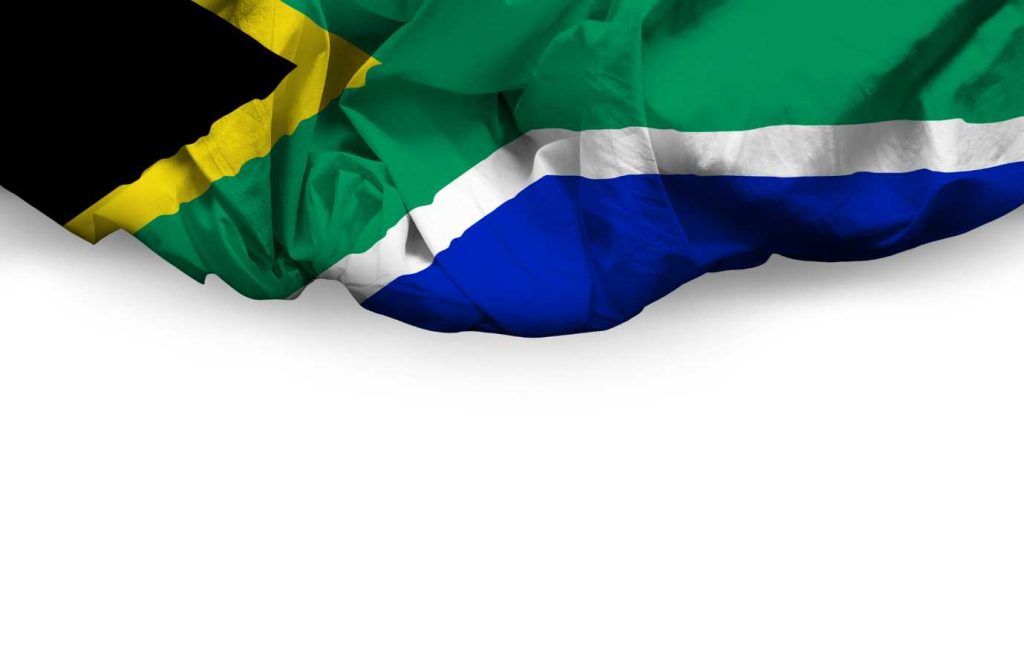 South African flag, folded and draped over a white background, with black, yellow, green, white, blue, and red stripes.