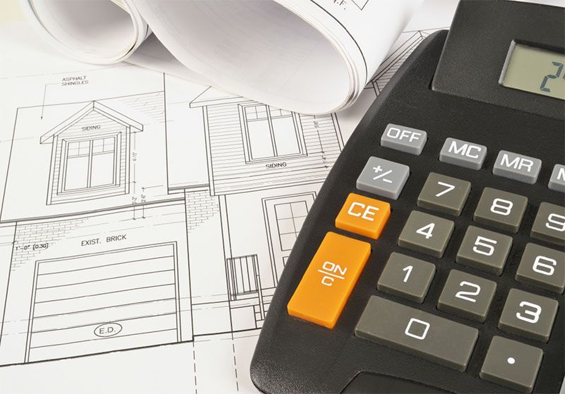 Calculator on house blueprints, suggesting construction cost estimation.