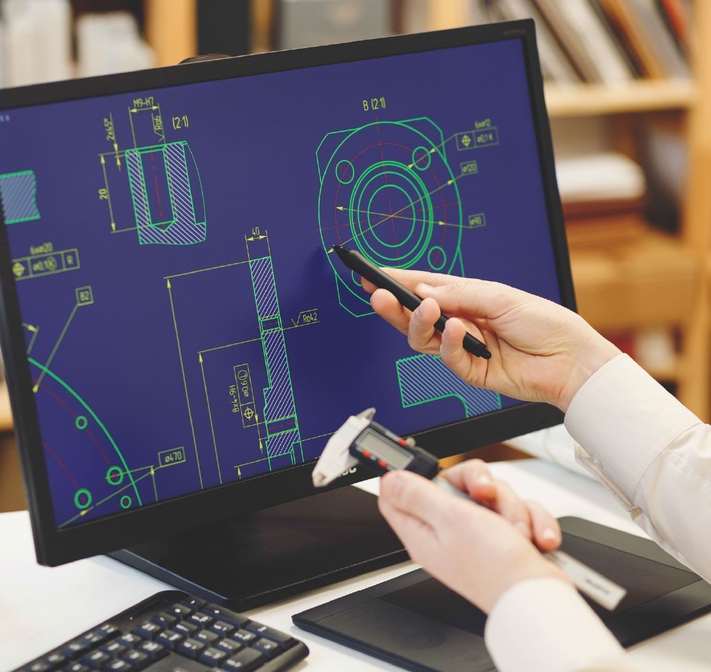 Person using a stylus to point at a mechanical blueprint on a computer monitor, with calipers in the other hand.
