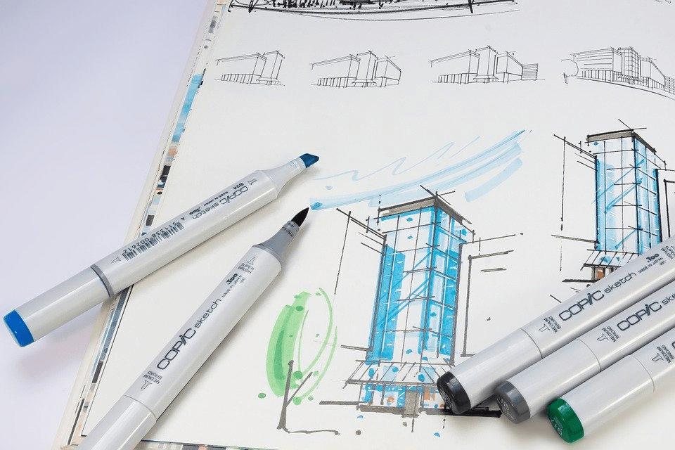 Markers on architectural sketches, including buildings and trees, with blue and green accents.