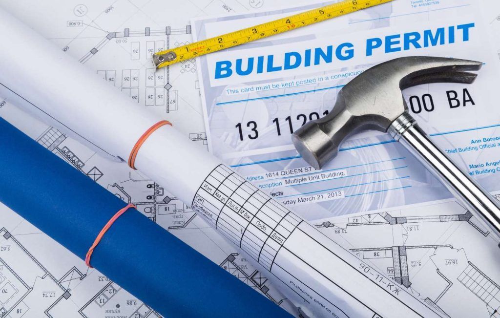 Building permit and blueprints with hammer and measuring tape.