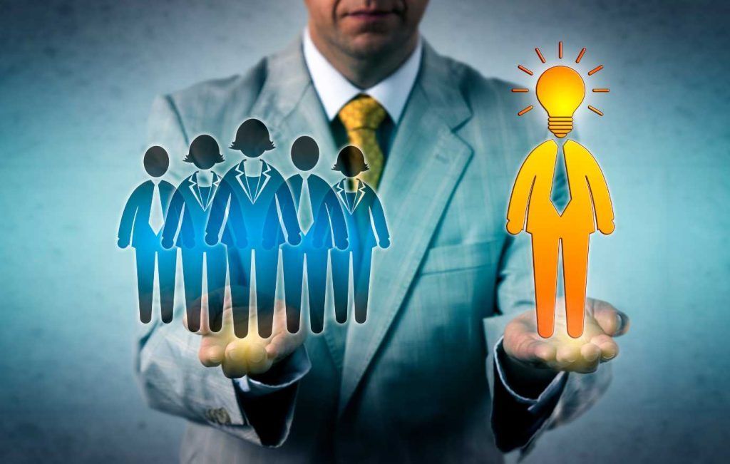 Businessman holding a team on one hand, a lightbulb-headed person on the other, symbolizing leadership and ideas.