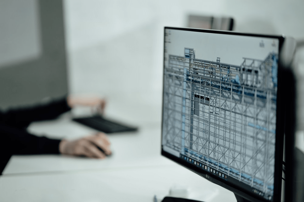 Person using a computer displaying architectural blueprints, focused on the screen.