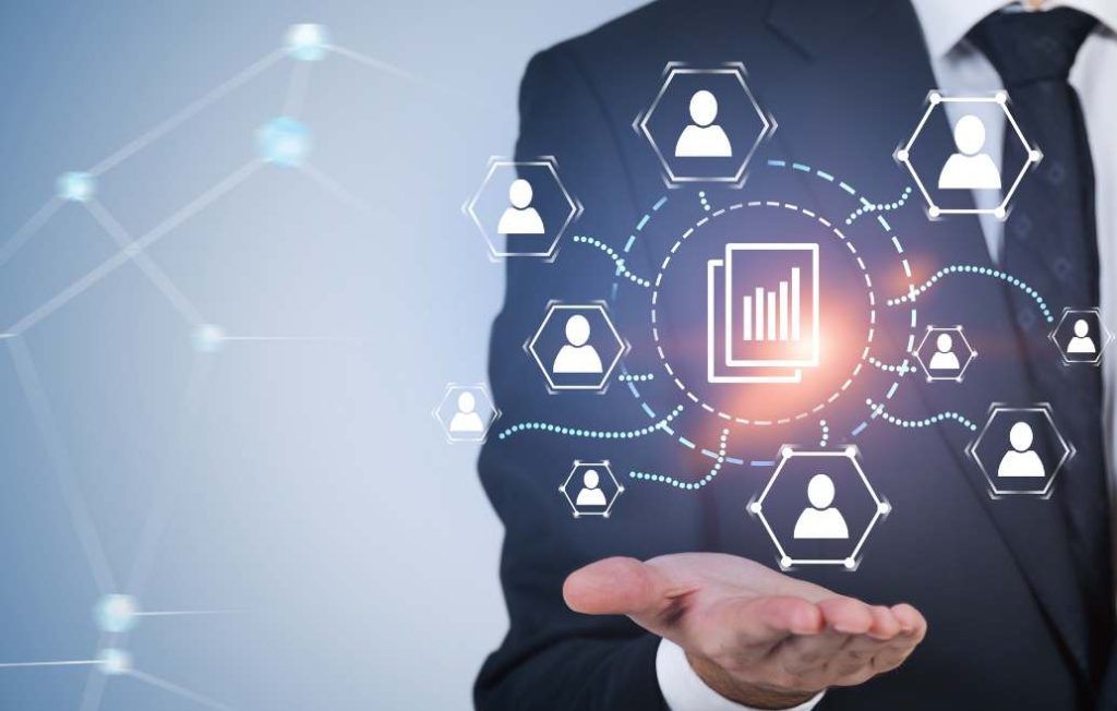 Businessman holding a glowing network of user icons and documents.