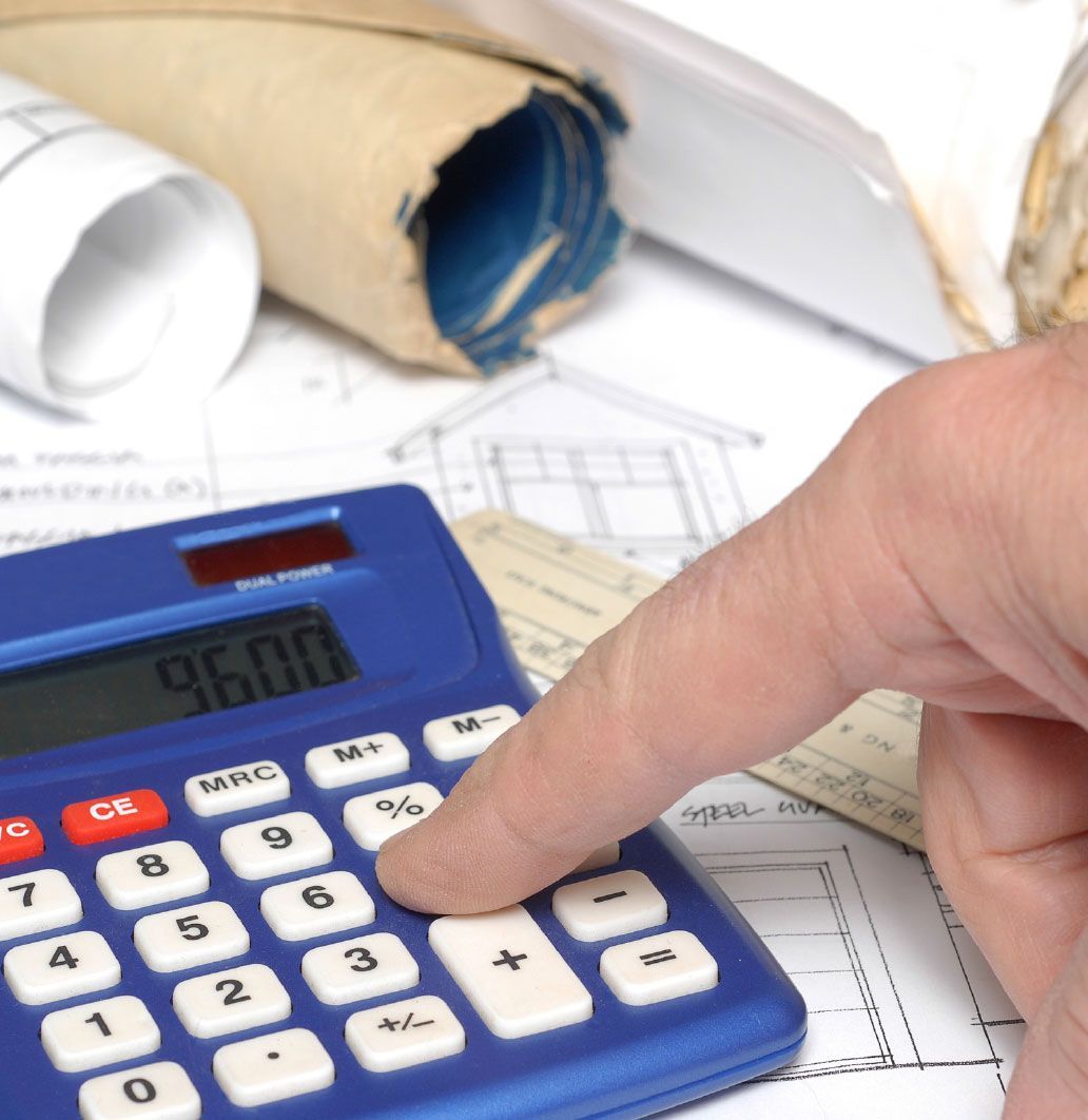 Person's hand using a blue calculator on top of architectural blueprints, displaying 