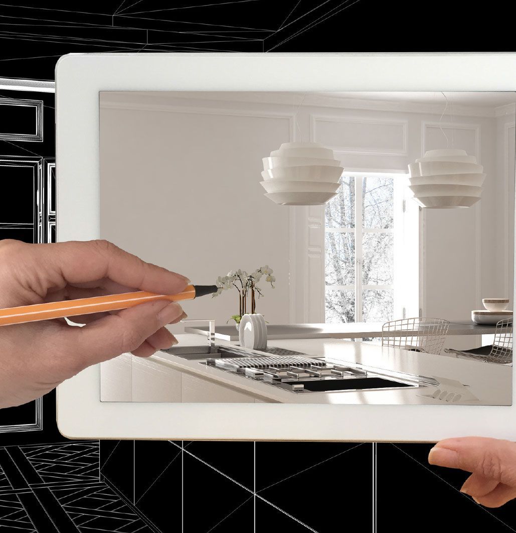 A hand holding a tablet displaying a kitchen, with a stylus pointing to the screen.