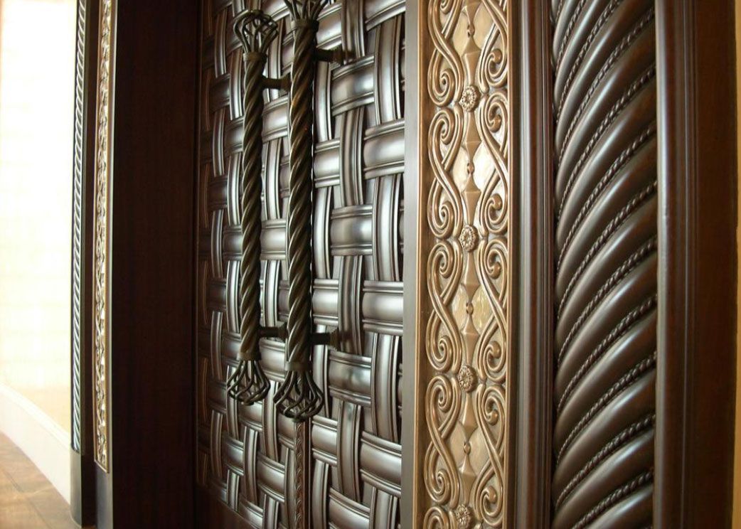 Ornate wooden door with woven texture, decorative trim, and rope-style handles.