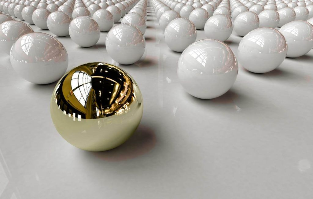 A gold sphere stands out among rows of white spheres on a reflective surface.