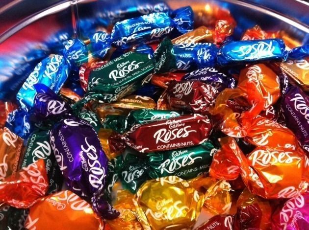 Cadbury Roses chocolates in colorful wrappers, piled in a silver bowl.