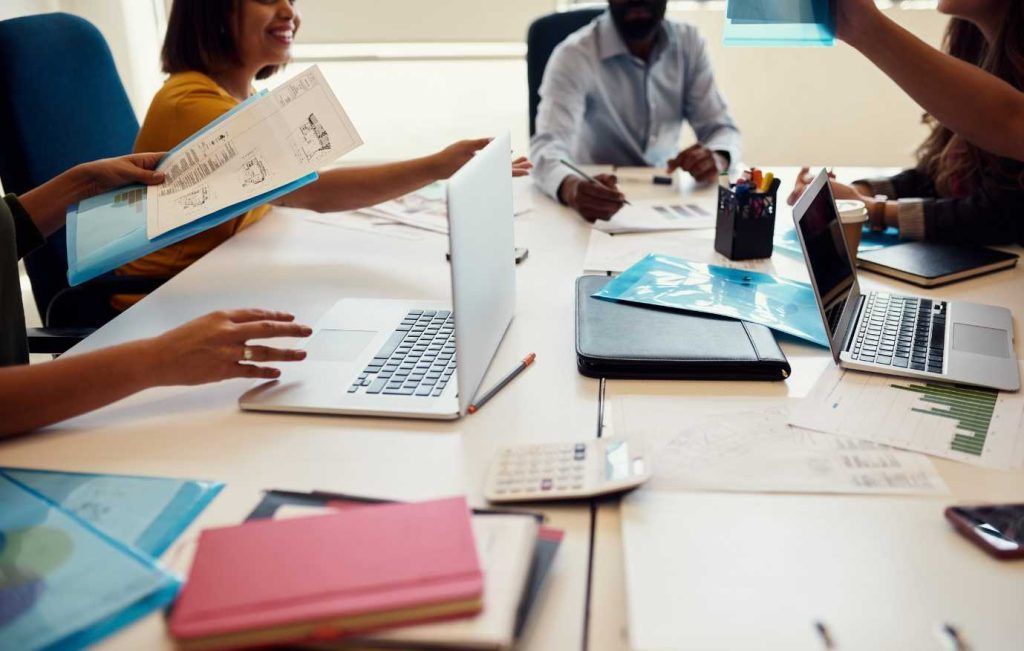 People at a table in an office collaborate on paperwork.