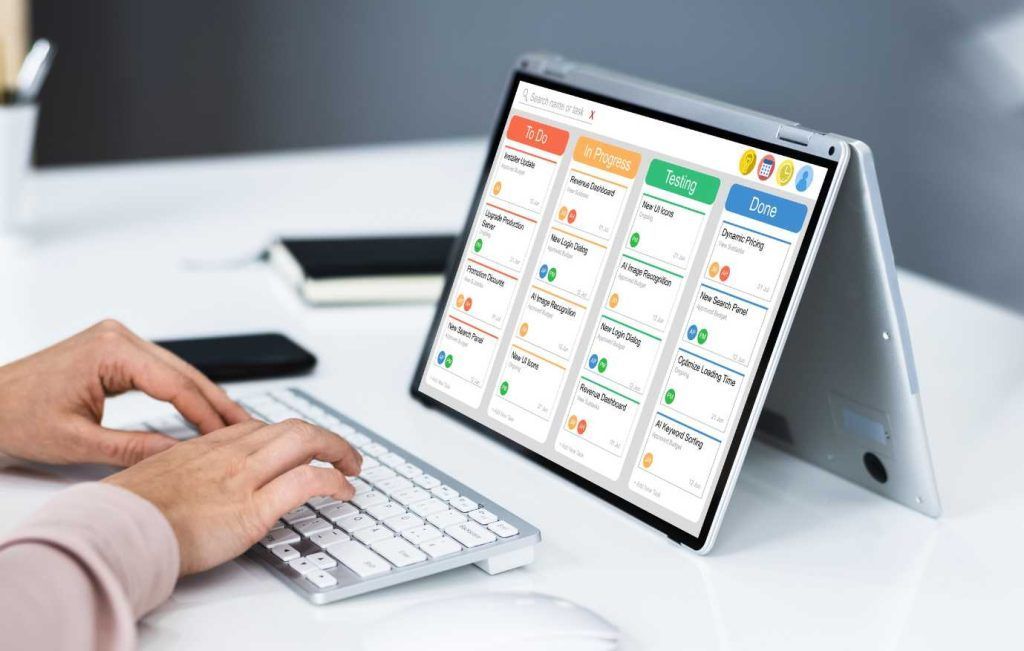 Person using a keyboard with a tablet showing a calendar app open on a desk.