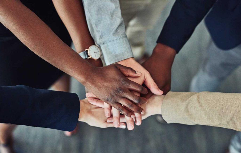 Hands of diverse people clasped together in a symbol of unity and teamwork.