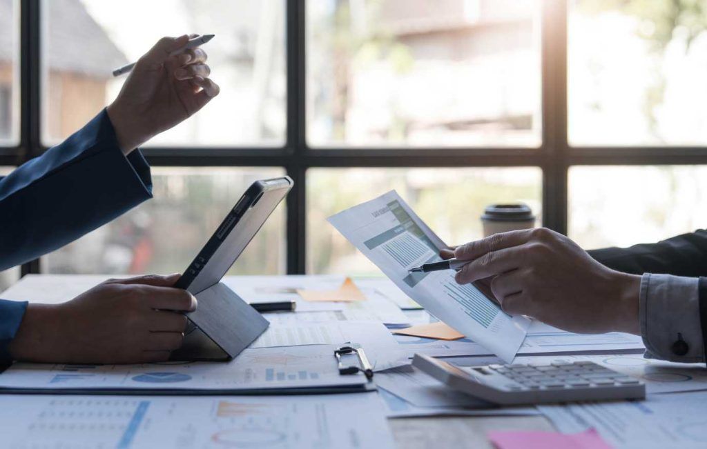 People reviewing financial documents at a desk, pointing and using a calculator.