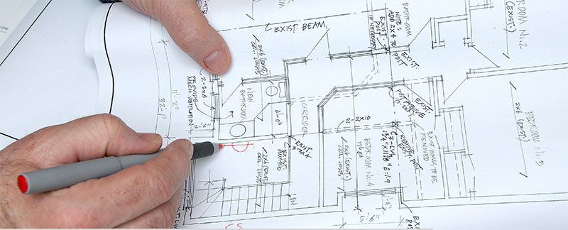 Hands pointing and drawing on architectural blueprints.