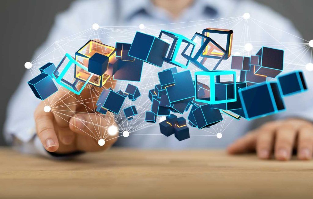 Person's hand interacting with floating blue and gold 3D cubes connected by white lines and dots.