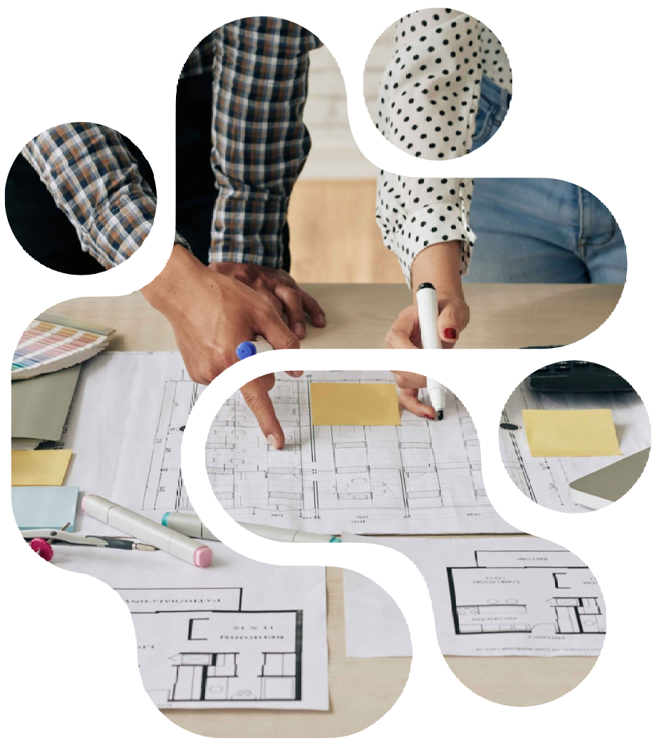 Two people reviewing architectural plans, pointing with pens, on a table with sticky notes.