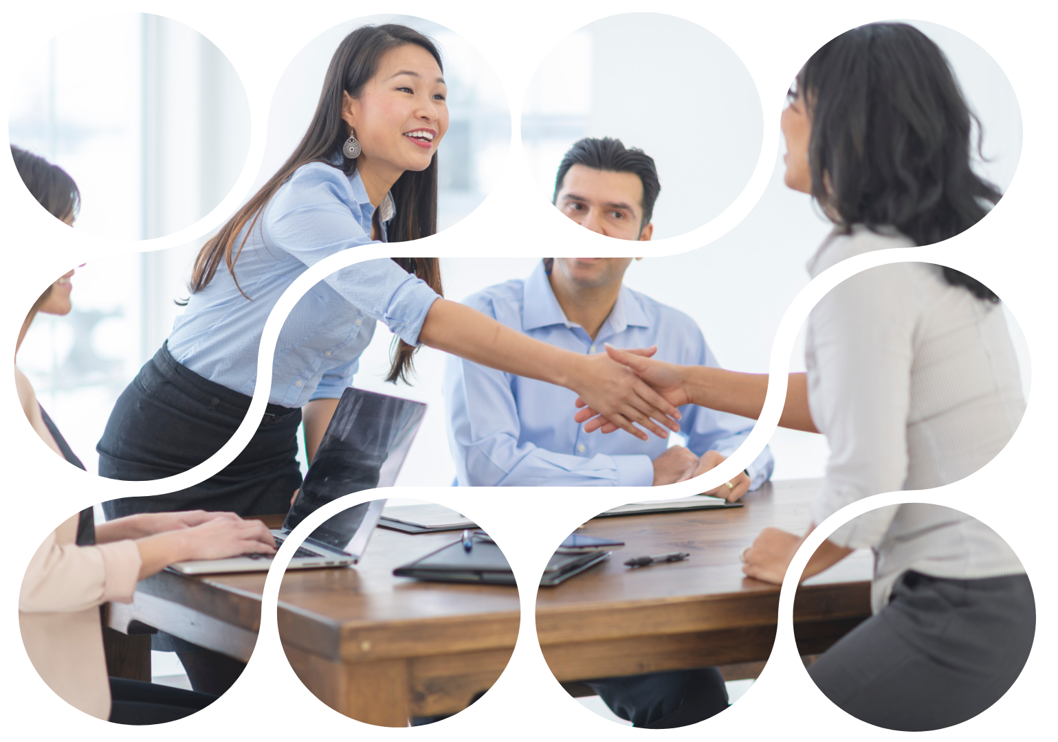 Business people shaking hands in an office, smiling, near a conference table.
