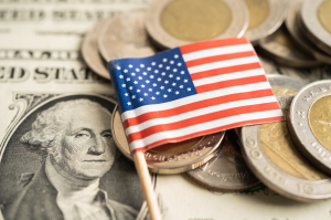 American flag on a pile of US dollar bills and various coins.