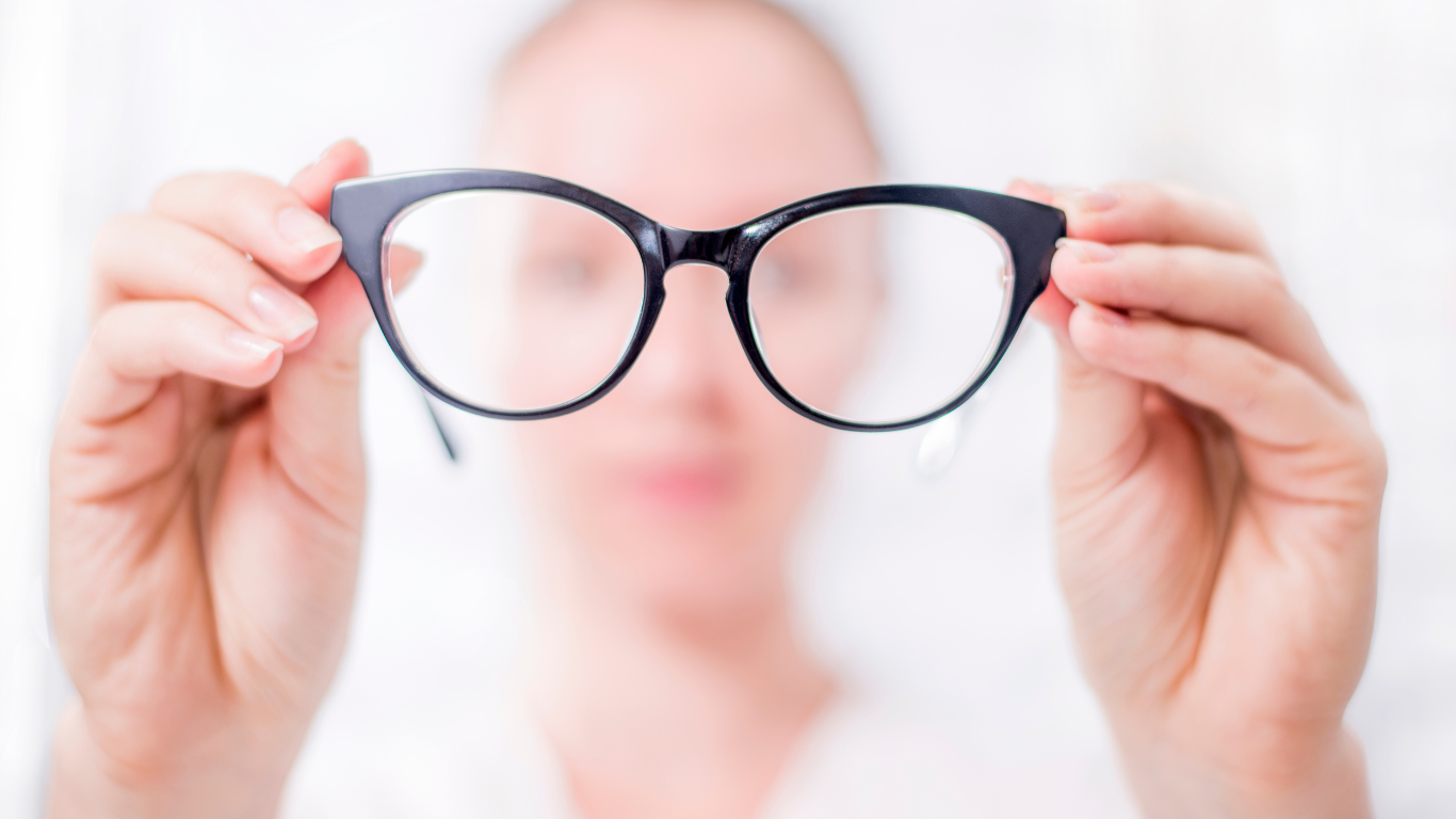 An elderly woman is wearing glasses and smiling.