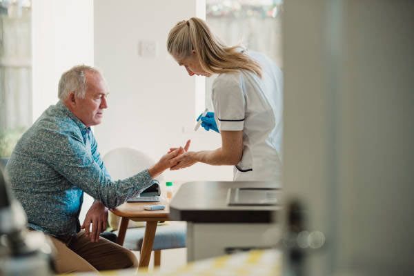 A nurse is holding the hand of an elderly man.