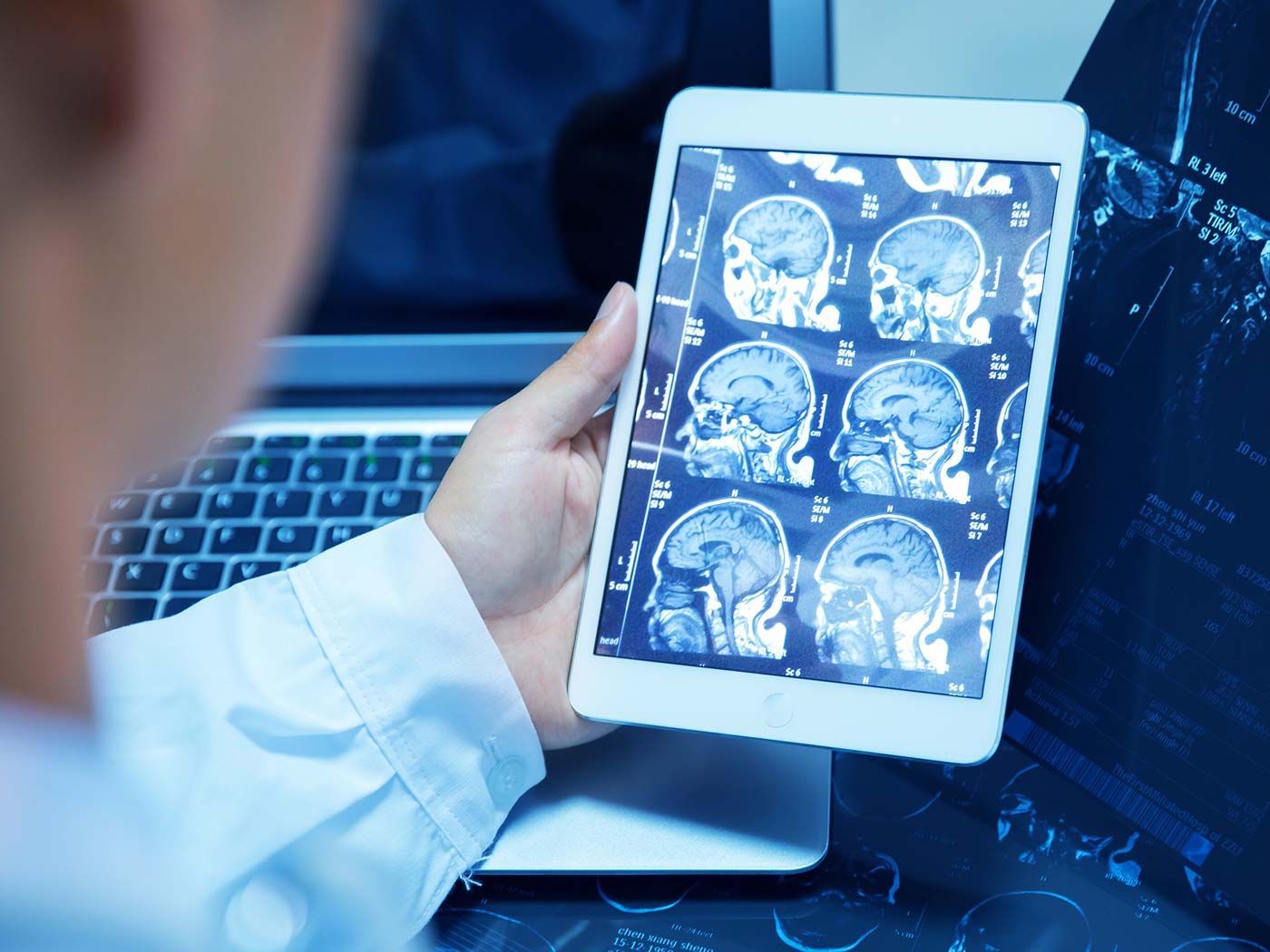 A person is holding a tablet with a picture of a brain on it.