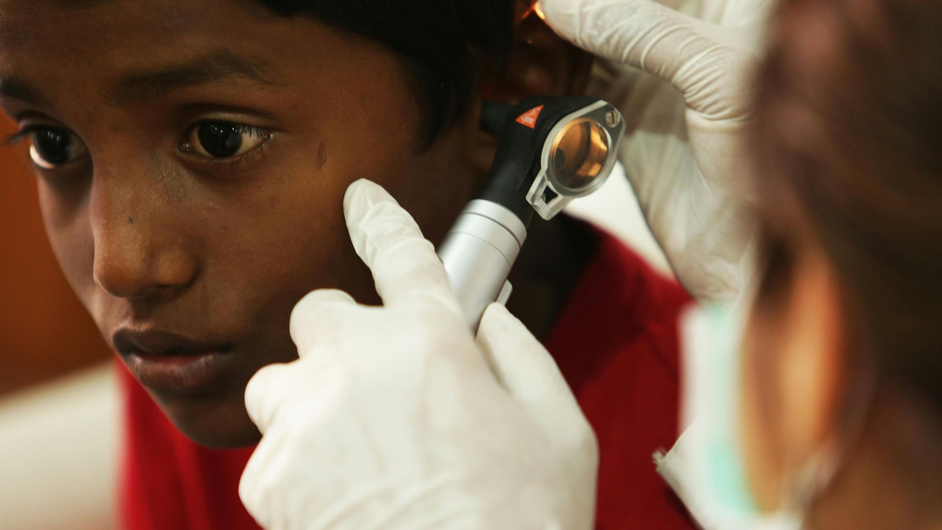A doctor examines a child 's ear with a magnifying glass