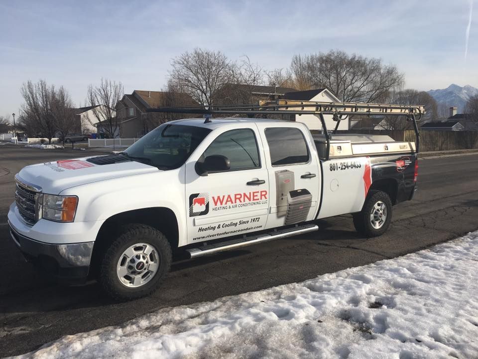 A white warner truck is parked on the side of the road in the snow.