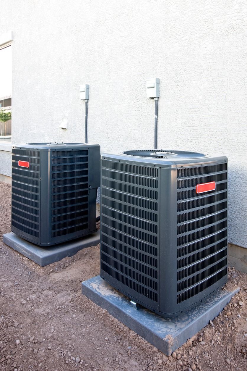 Two air conditioners are sitting on the side of a building.