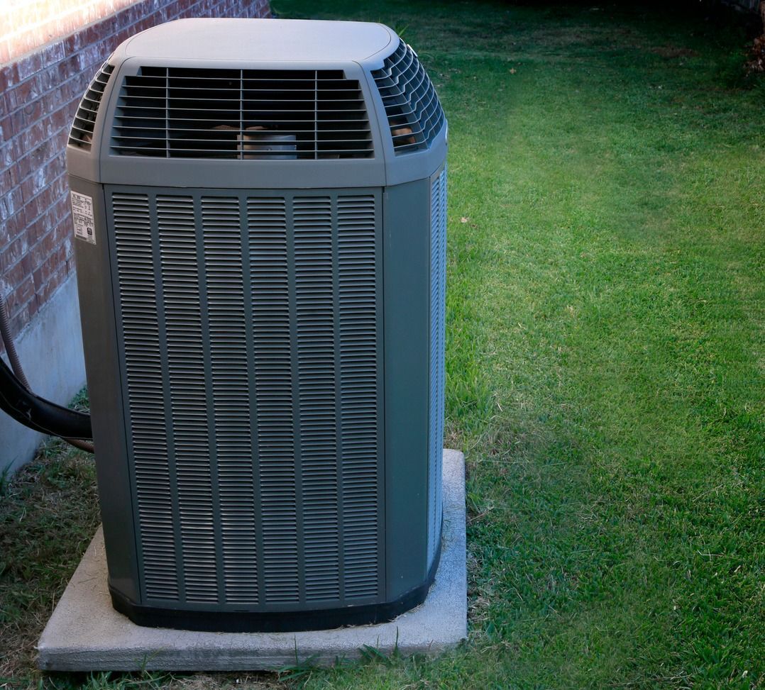 A large air conditioner is sitting on top of a concrete base in a backyard.
