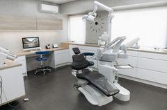 Dental office with dental chair, equipment, and cabinets.