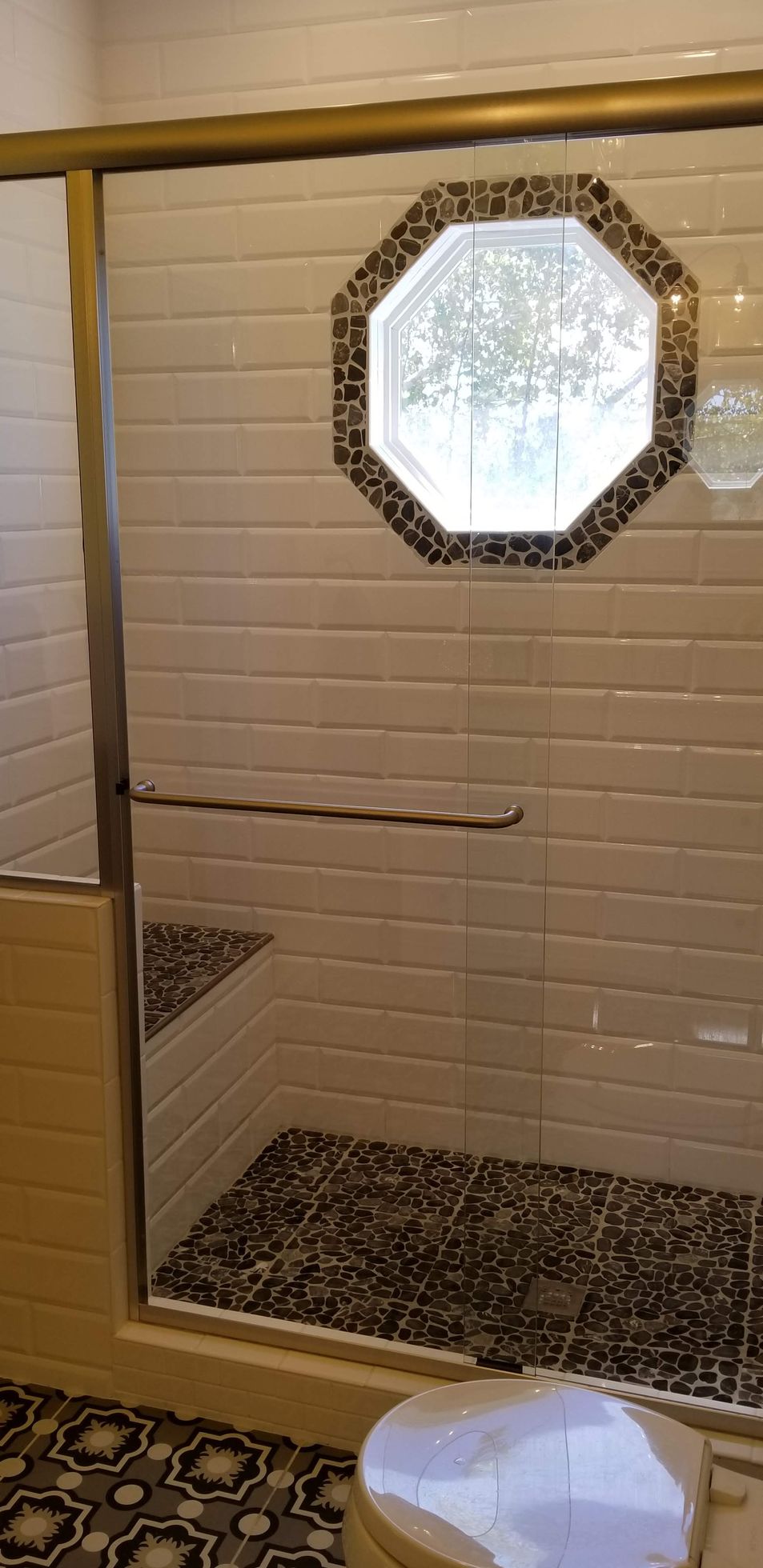 A bathroom with a walk in shower and a window.