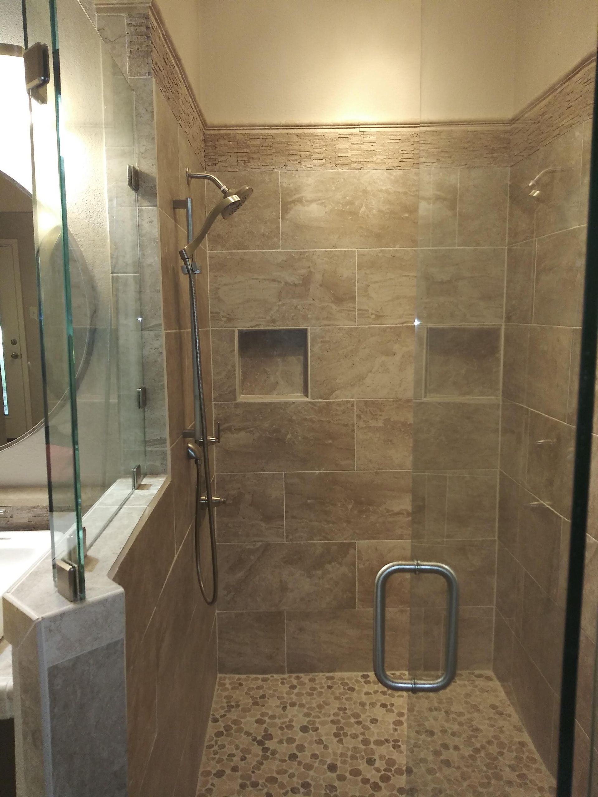 A bathroom with a walk in shower with a glass door.