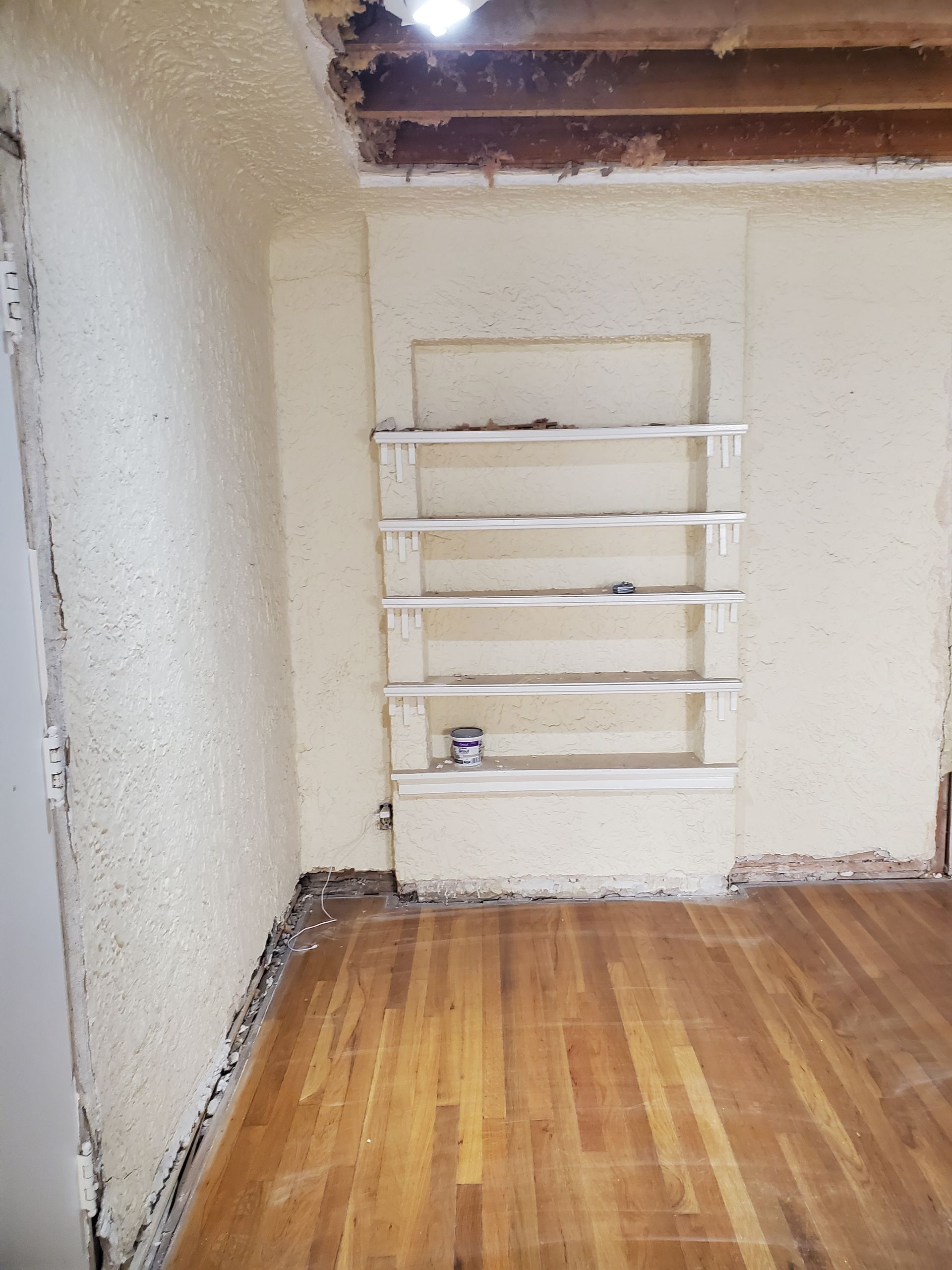 A room with a wooden floor and a shelf on the wall.