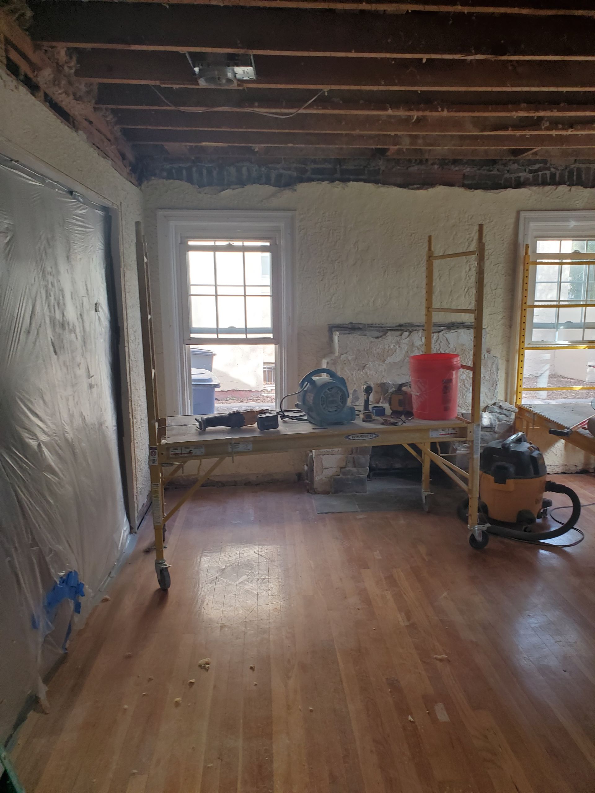 A room with wooden floors , a table and a vacuum cleaner in it.