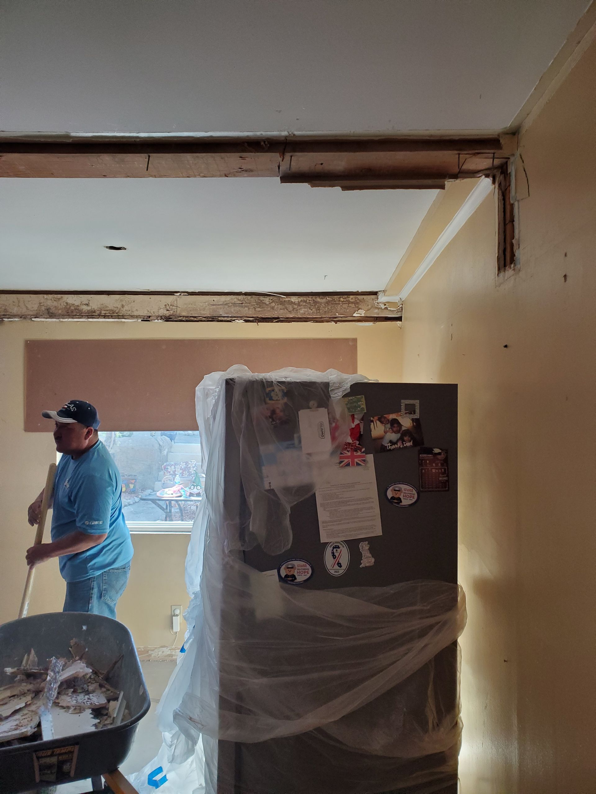 A man is standing next to a refrigerator in a room.