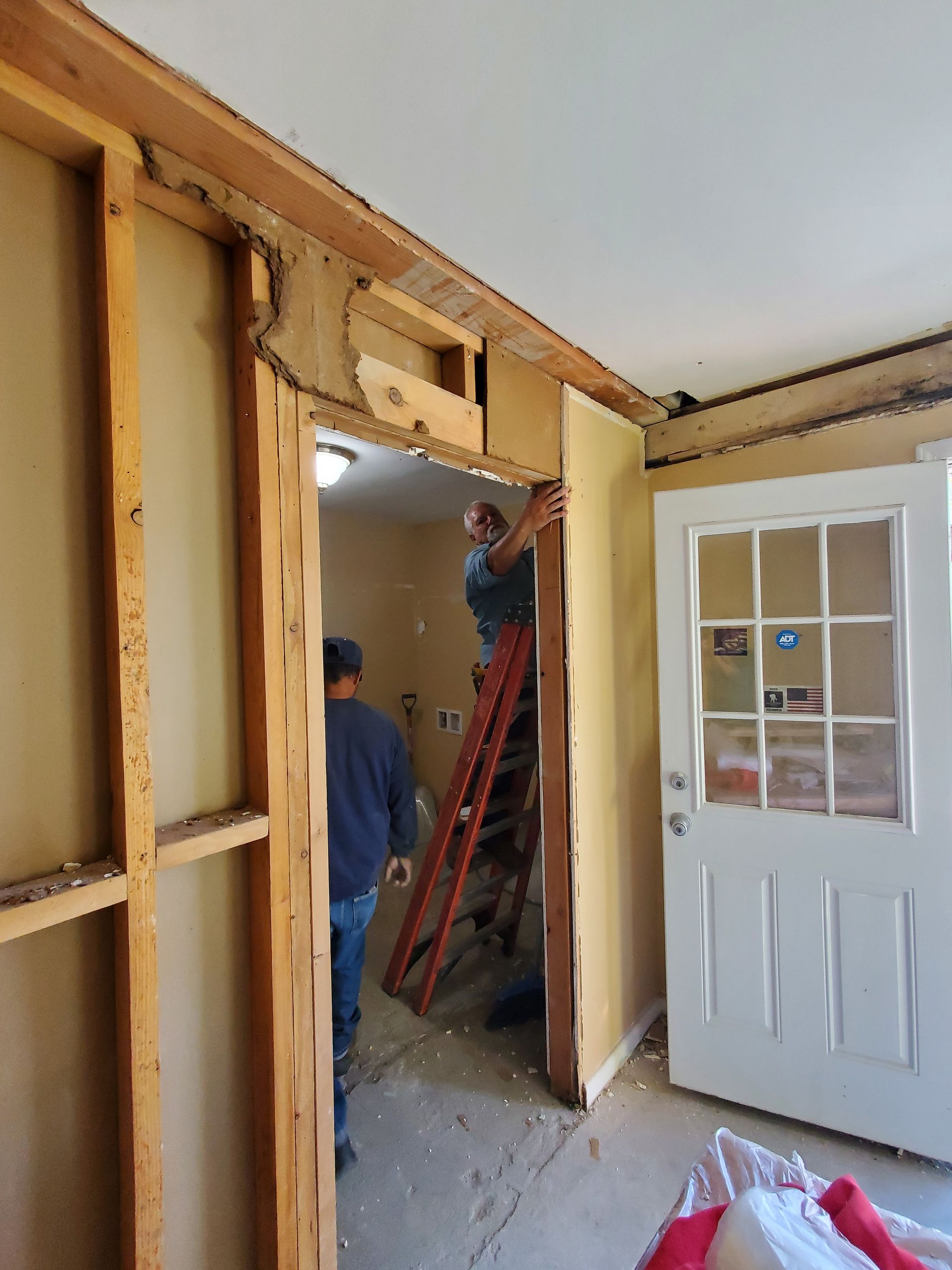 A man is standing on a ladder in a room next to a door.