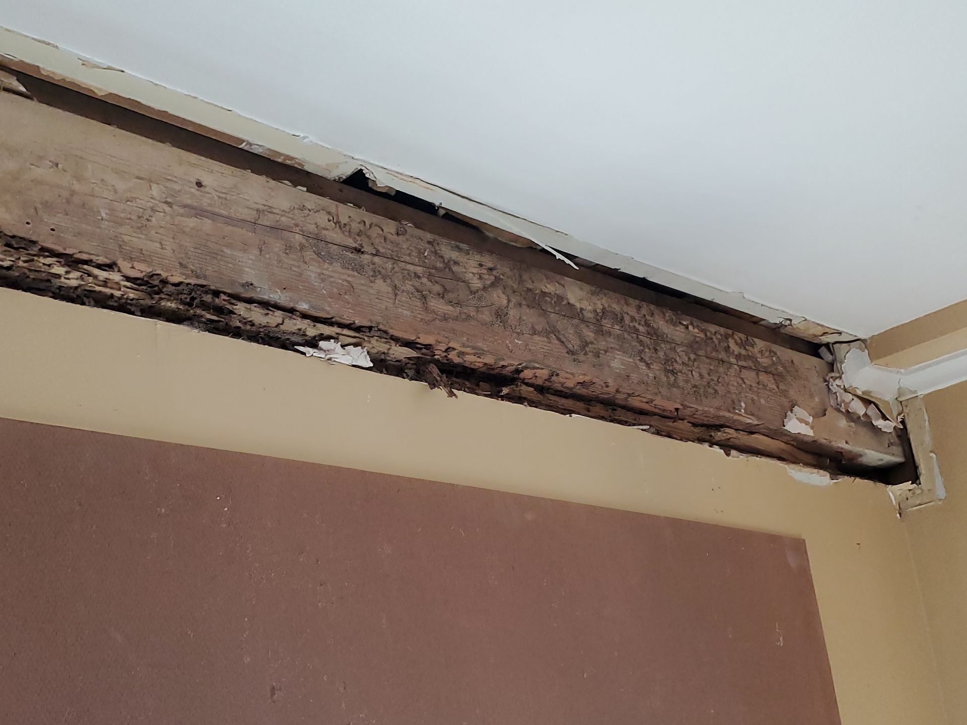 A wooden beam is missing from the ceiling of a room.