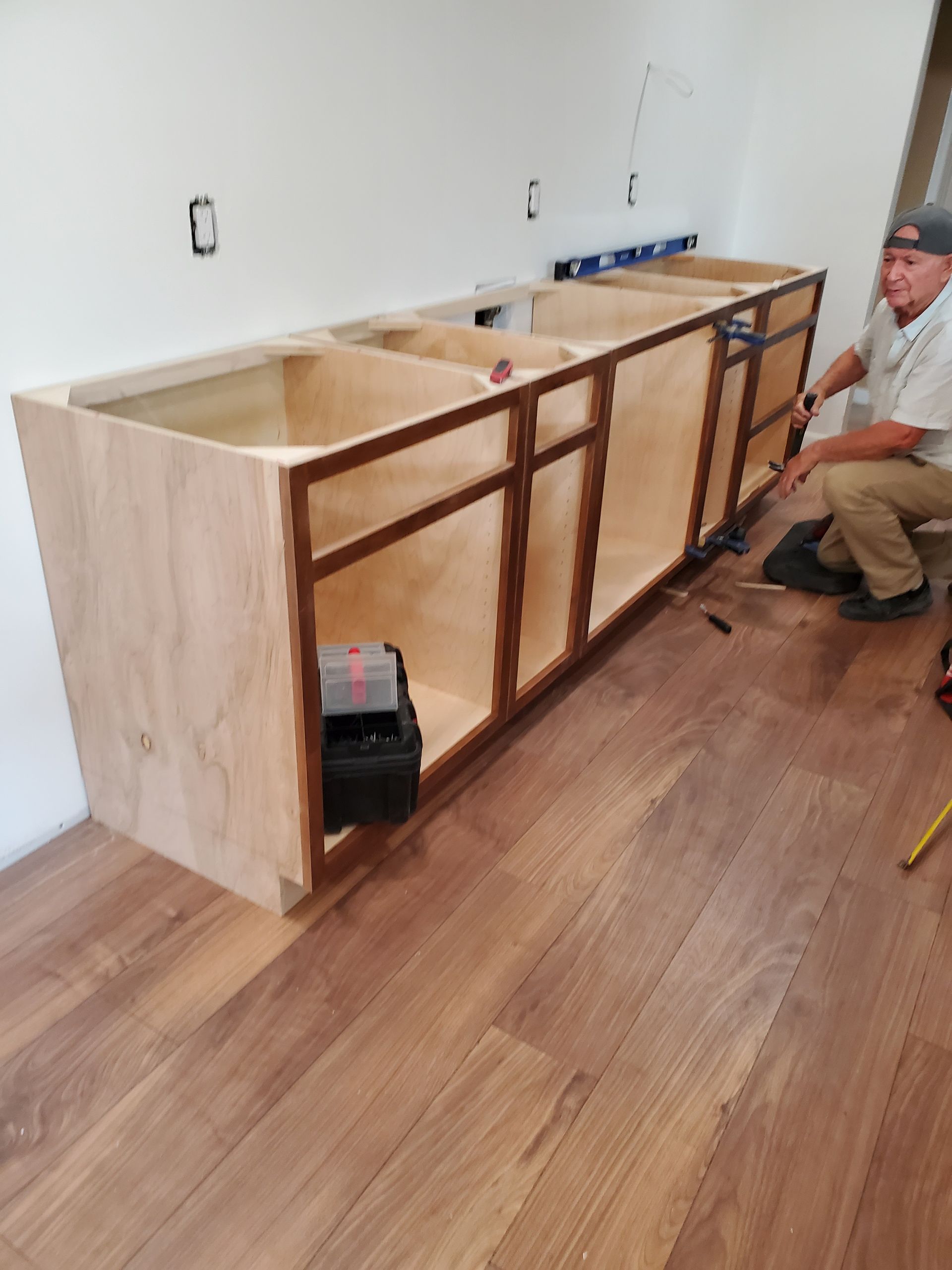 A man is measuring a cabinet in a kitchen