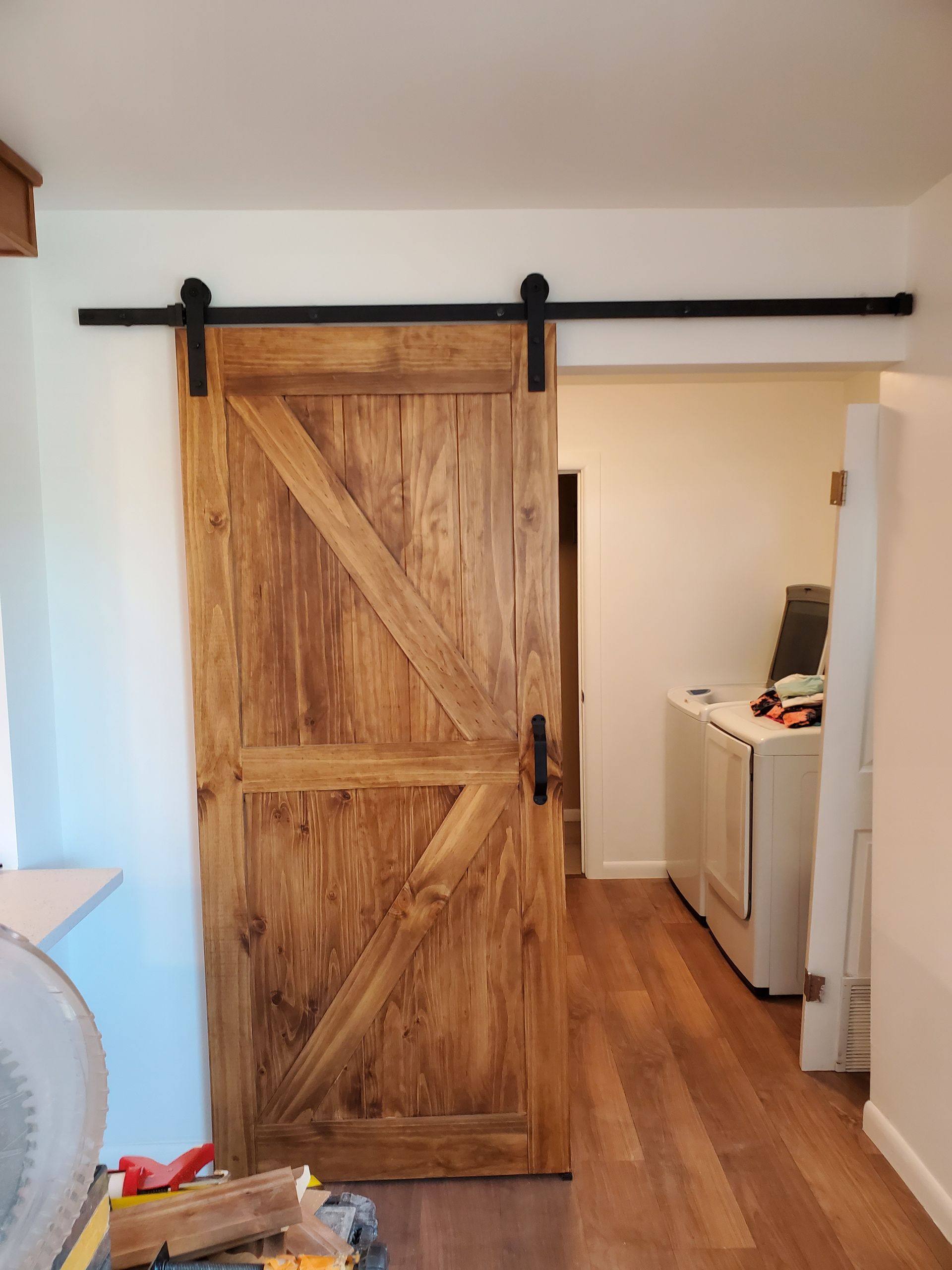 A wooden sliding barn door is open in a laundry room.