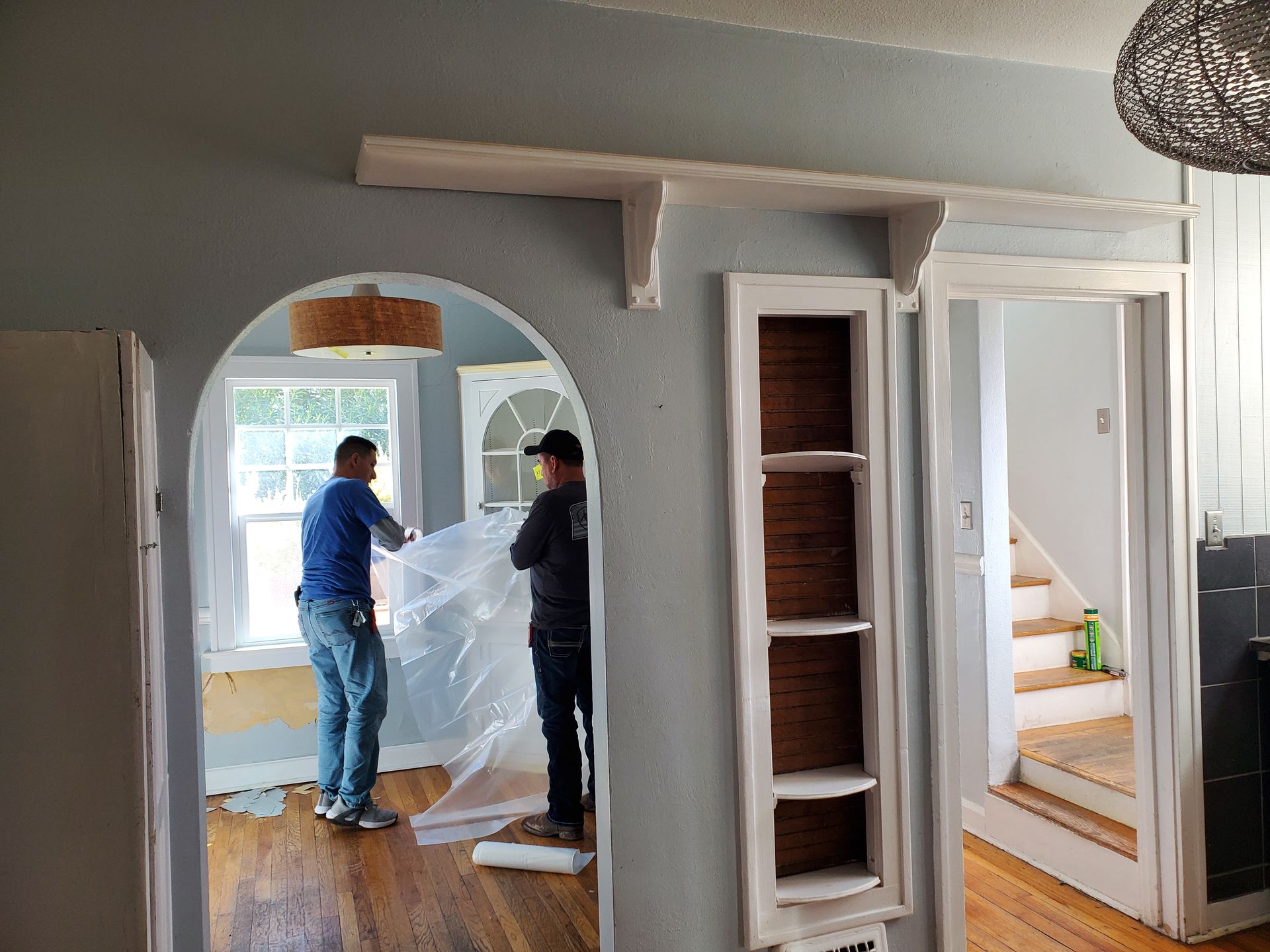 Two men are standing in a hallway in a house.