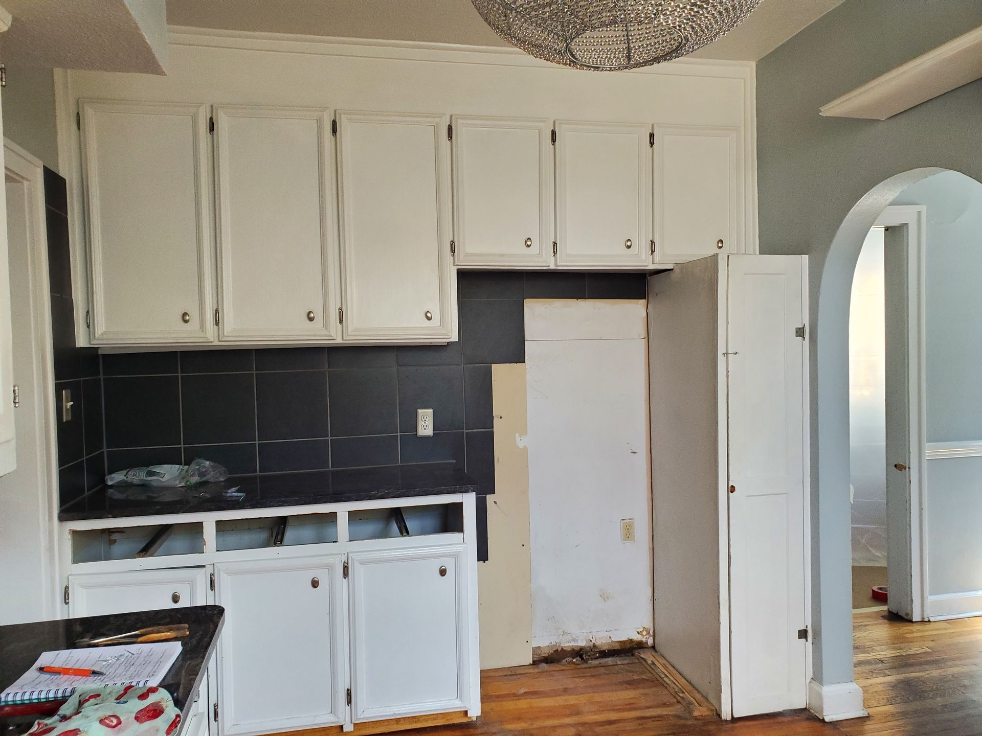 An empty kitchen with white cabinets and black tiles