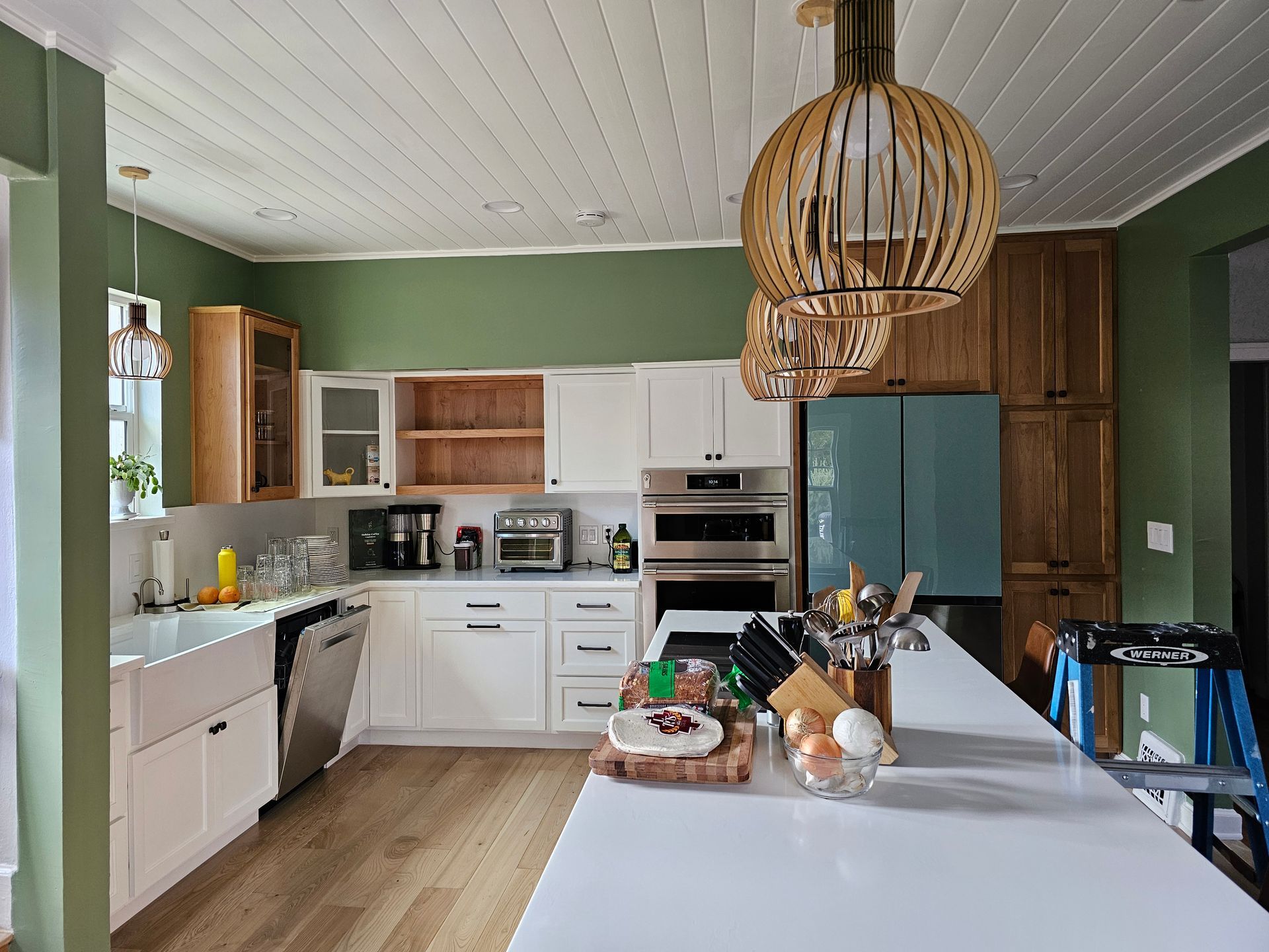A kitchen with white cabinets , wooden cabinets , stainless steel appliances and a large island.