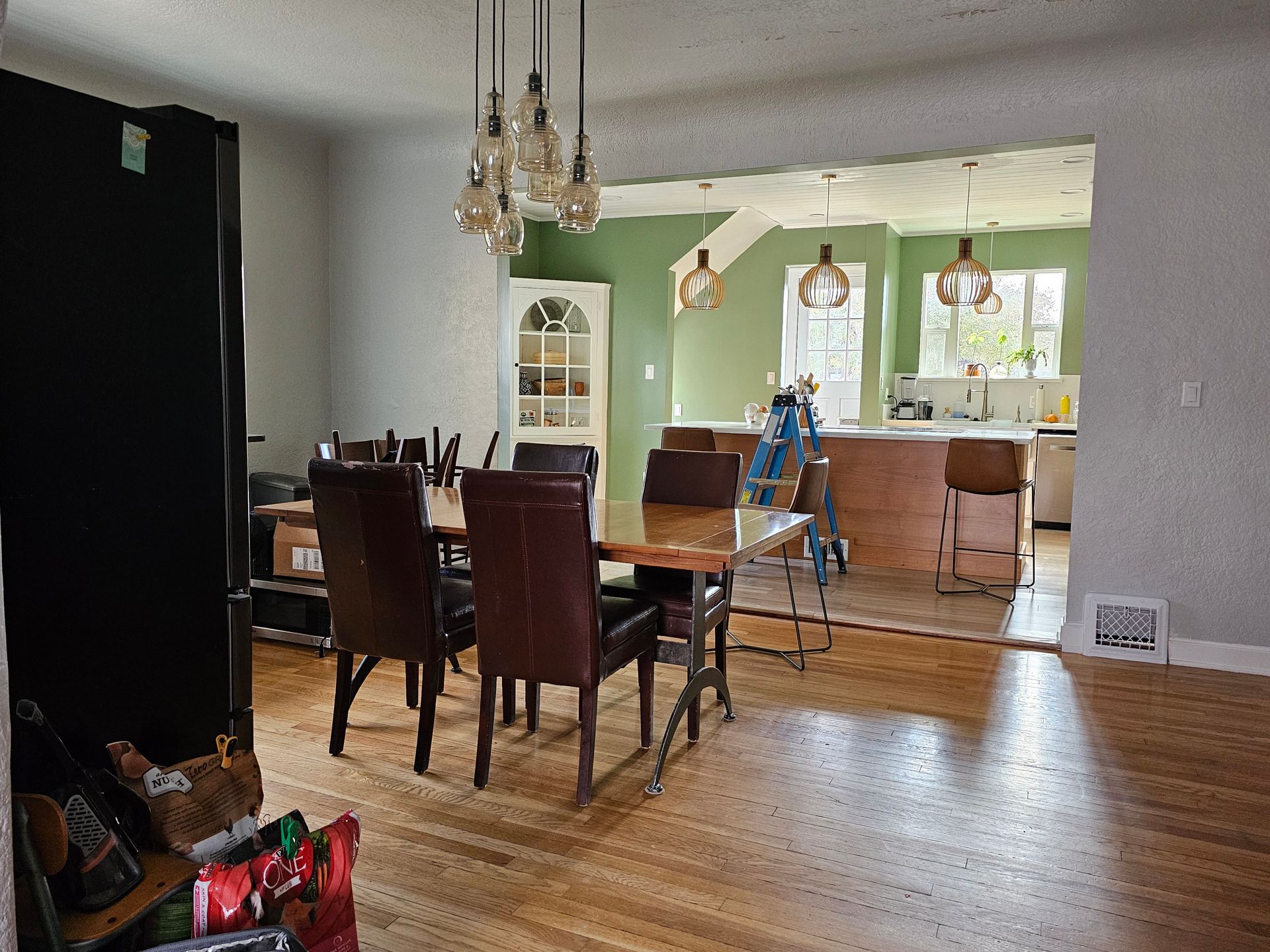 A dining room with a table and chairs and a kitchen in the background.