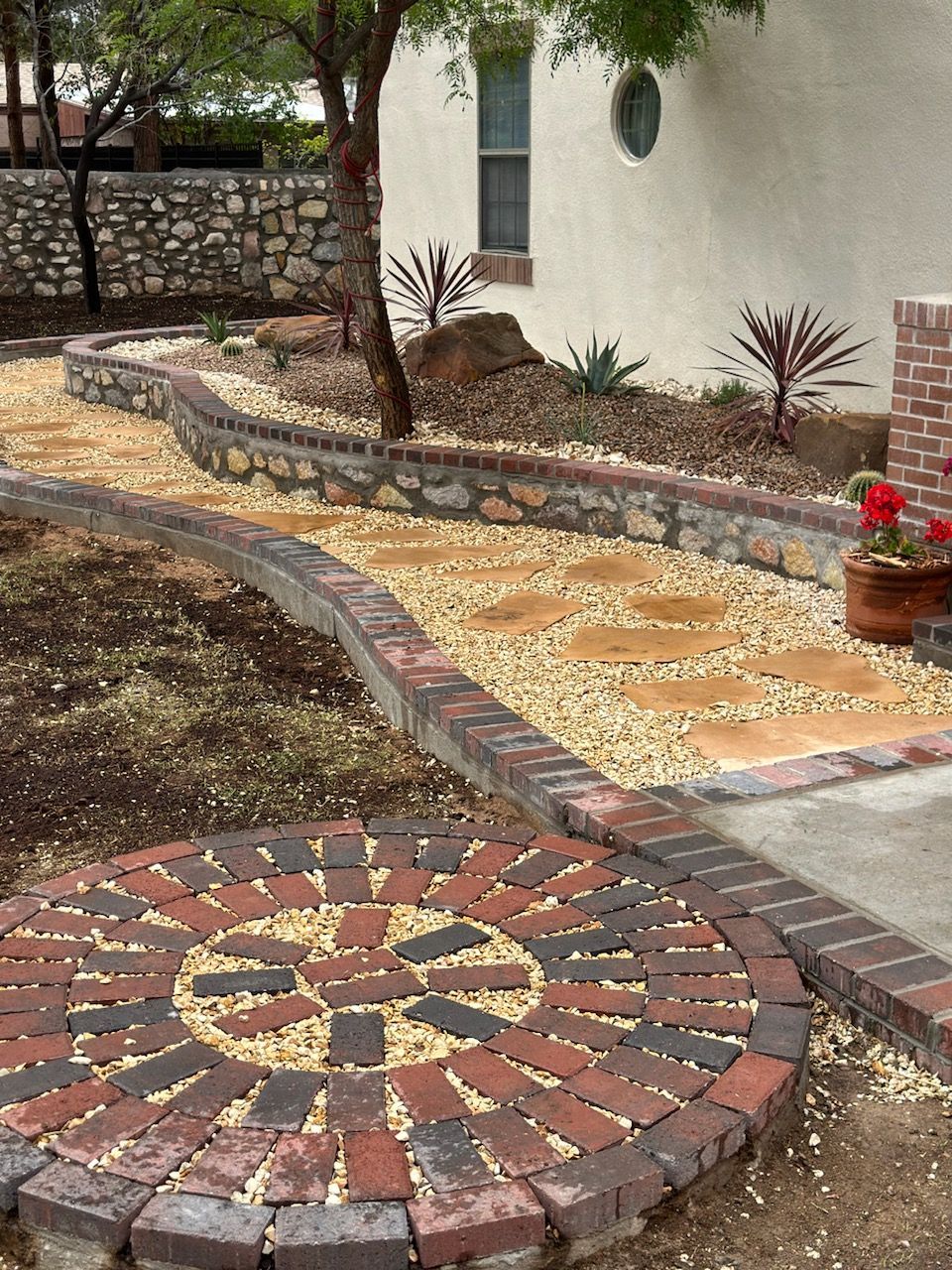 A brick walkway with a circular design in the middle