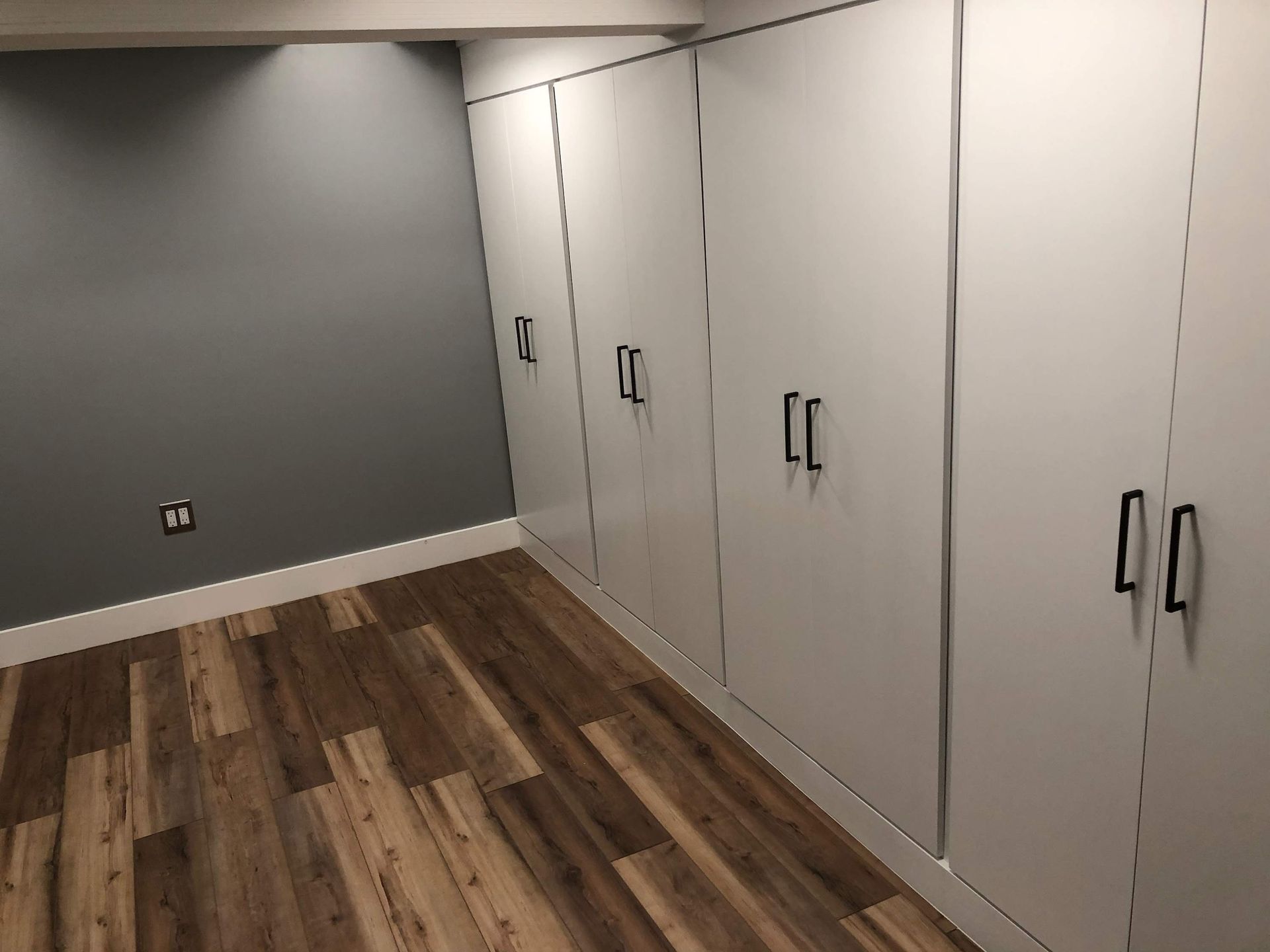 A room with hardwood floors and white cabinets.